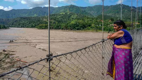 A woman looks at the indundated area after flash floods, in the Devghat area, Nepal, Thursday, Aug. 27, 2026