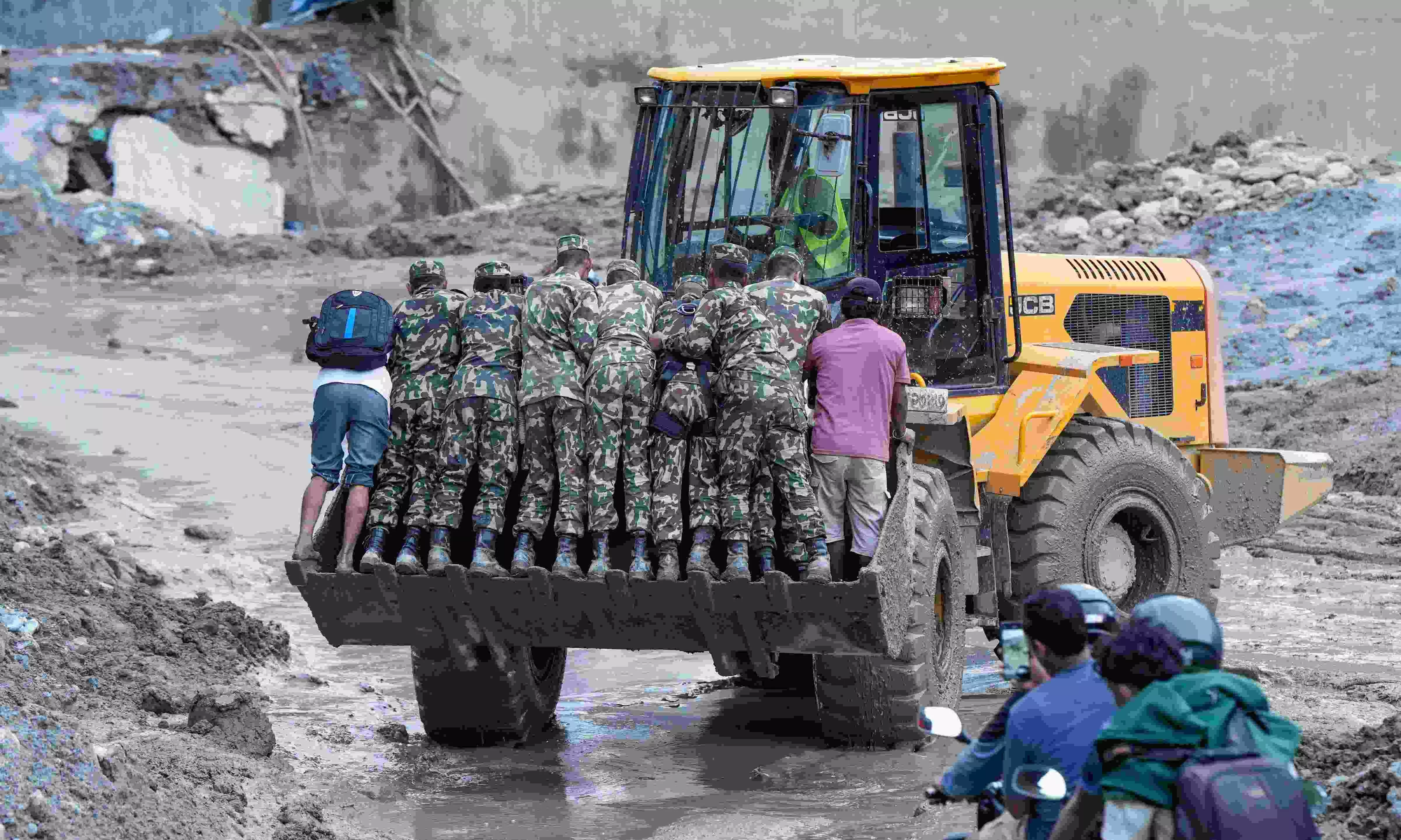 Security personnel stand on an excavator at a muddy area in the aftermath of flash floods, at Trishuli market, in Nuwakot district in Nepal Security personnel stand on an excavator at a muddy area in the aftermath of flash floods, at Trishuli market, in Nuwakot district in Nepal