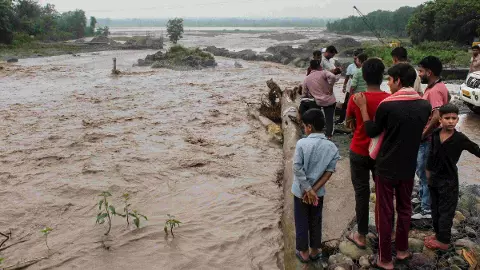 People gather near an overflowing causeway as the swollen Bin river flows following incessant heavy rainfall, in Rishikesh, Uttarakhand People gather near an overflowing causeway as the swollen Bin river flows following incessant heavy rainfall, in Rishikesh, Uttarakhand